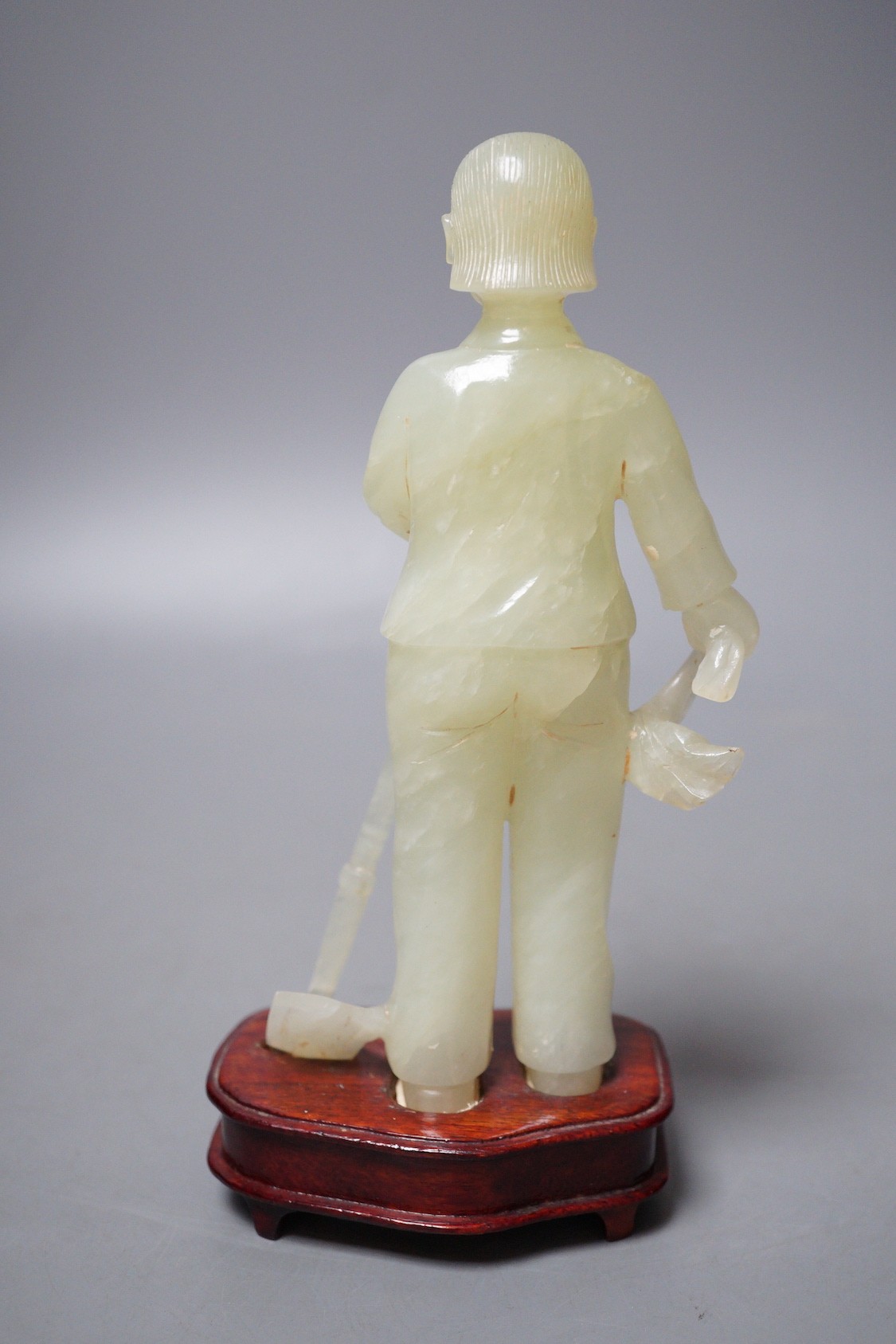 A Chinese carved bowenite jade figure of a worker on hardwood stand, 19cm